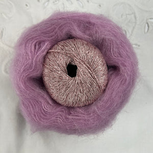 Ball of metallic pale pink yarn nestled inside a skein of cool rose pink brushed alpaca and silk yarn.