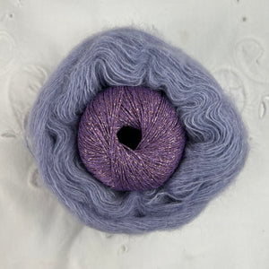 Ball of metallic lavender yarn nestled inside a skein of lavender brushed alpaca and silk yarn.