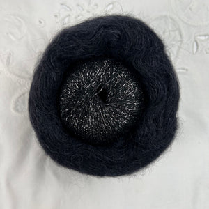 Ball of metallic black with silver yarn nestled inside a skein of black brushed alpaca and silk yarn.