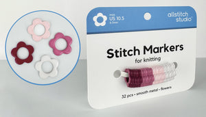 All Stitch Studio flower-shaped stitch markers in pink, white, and burgundy, shown on their retail packaging card alongside a circular inset detail view.