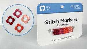 Allstitch Studio Stitch Markers for knitting, shown in their blue and white retail packaging with an inset circle displaying four flower-shaped metal markers in red, pink, and orange.